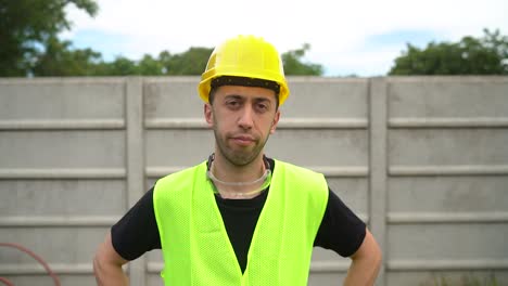 front portrait of laborer looking at camera, wearing hard hat and reflective safety vest