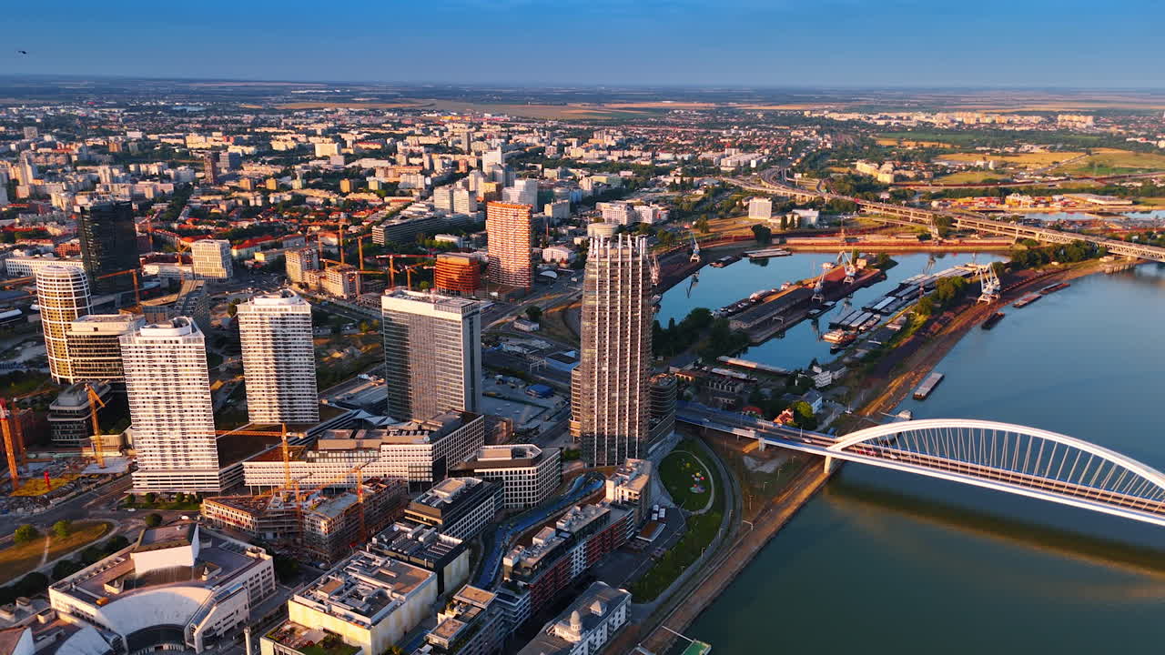 Bratislava skyline on a clear day. High above Bratislava, modern buildings shine against the blue sky, showcasing the vibrant urban landscape and river