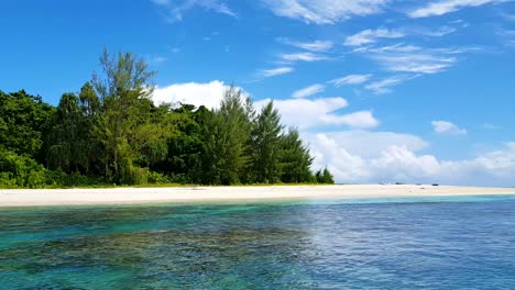 Stunning-remote-tropical-island-with-white-sandy-beach,-green-trees-and-beautiful-crystal-clear-turquoise-ocean-water-in-Papua-New-Guinea