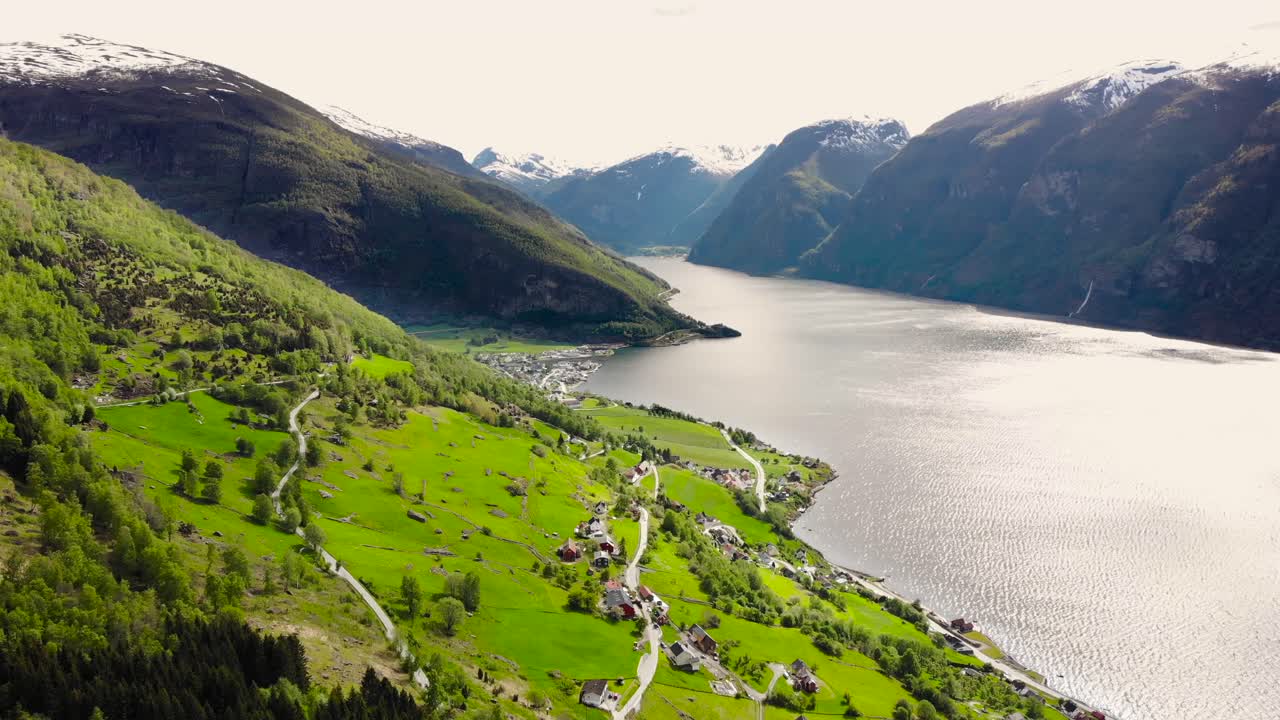 aérea: volando sobre el fiordo sognefjord desde la ladera de una montaña y una ciudad al fondo