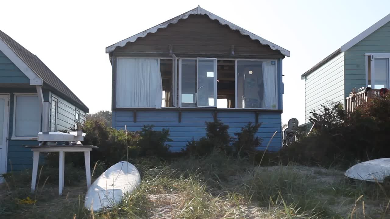 Casa blu e tavola da surf sulla spiaggia, Costa Giurassica dell'Inghilterra, ripresa statica