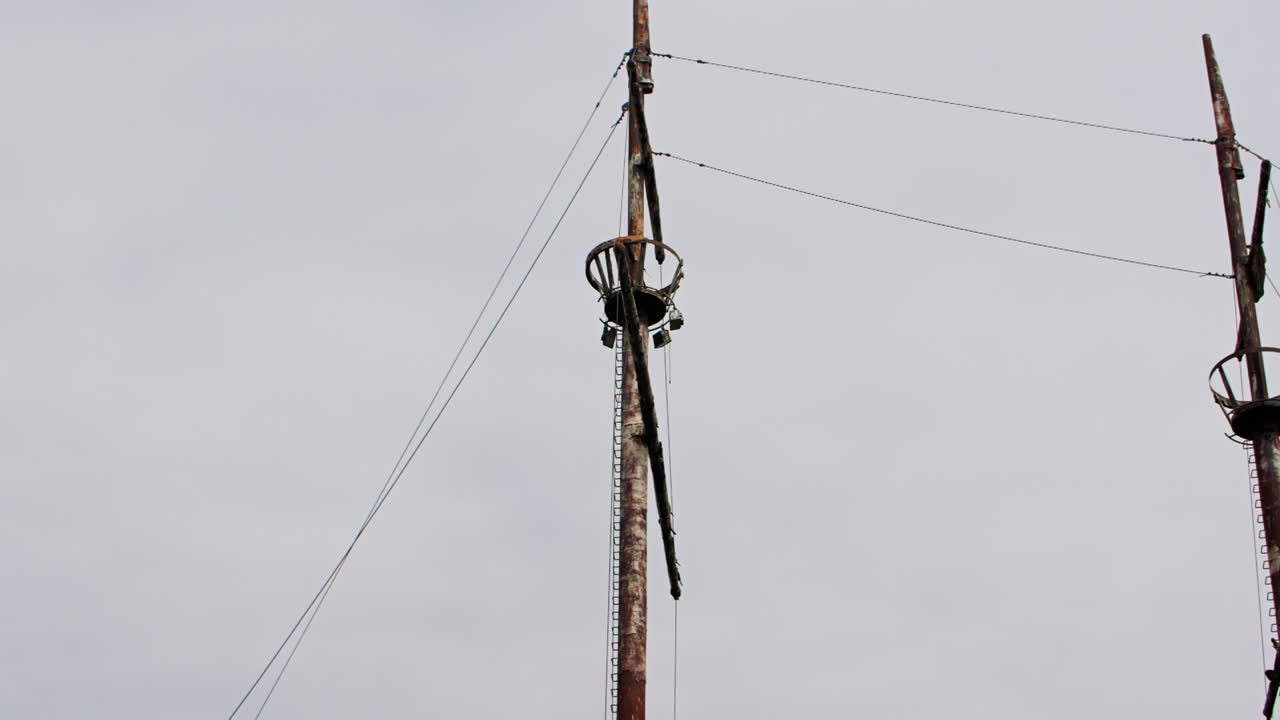 Mast of rusty red shipwreck stuck in shallow green water