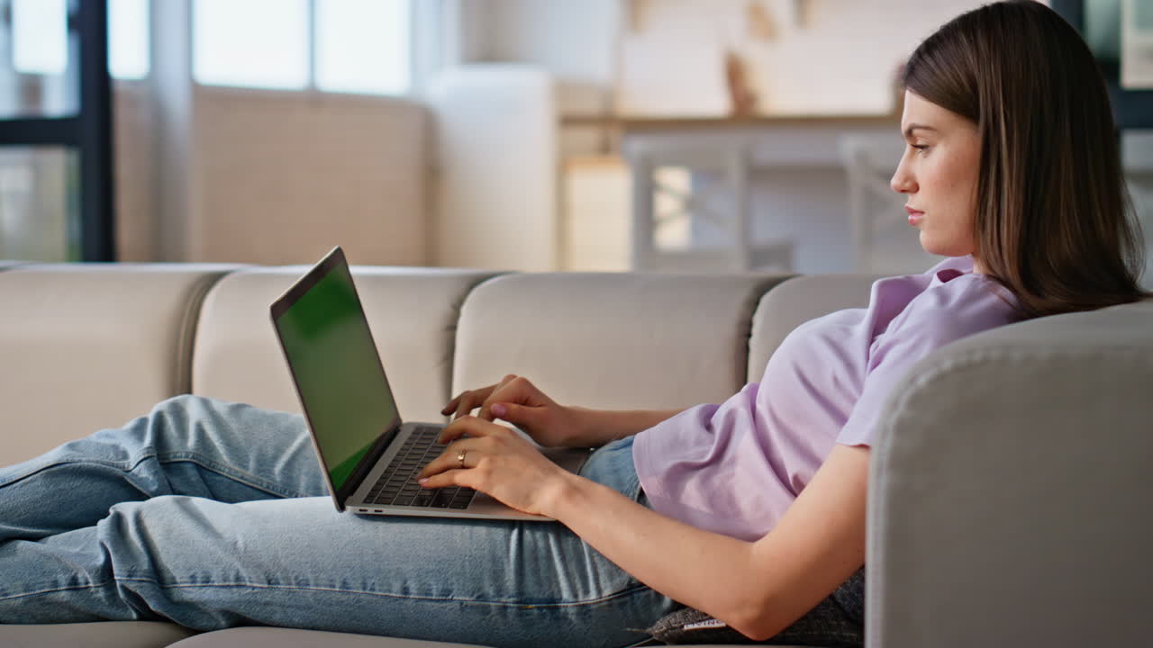 Girl using greenscreen laptop computer at sofa closeup. Online student studying