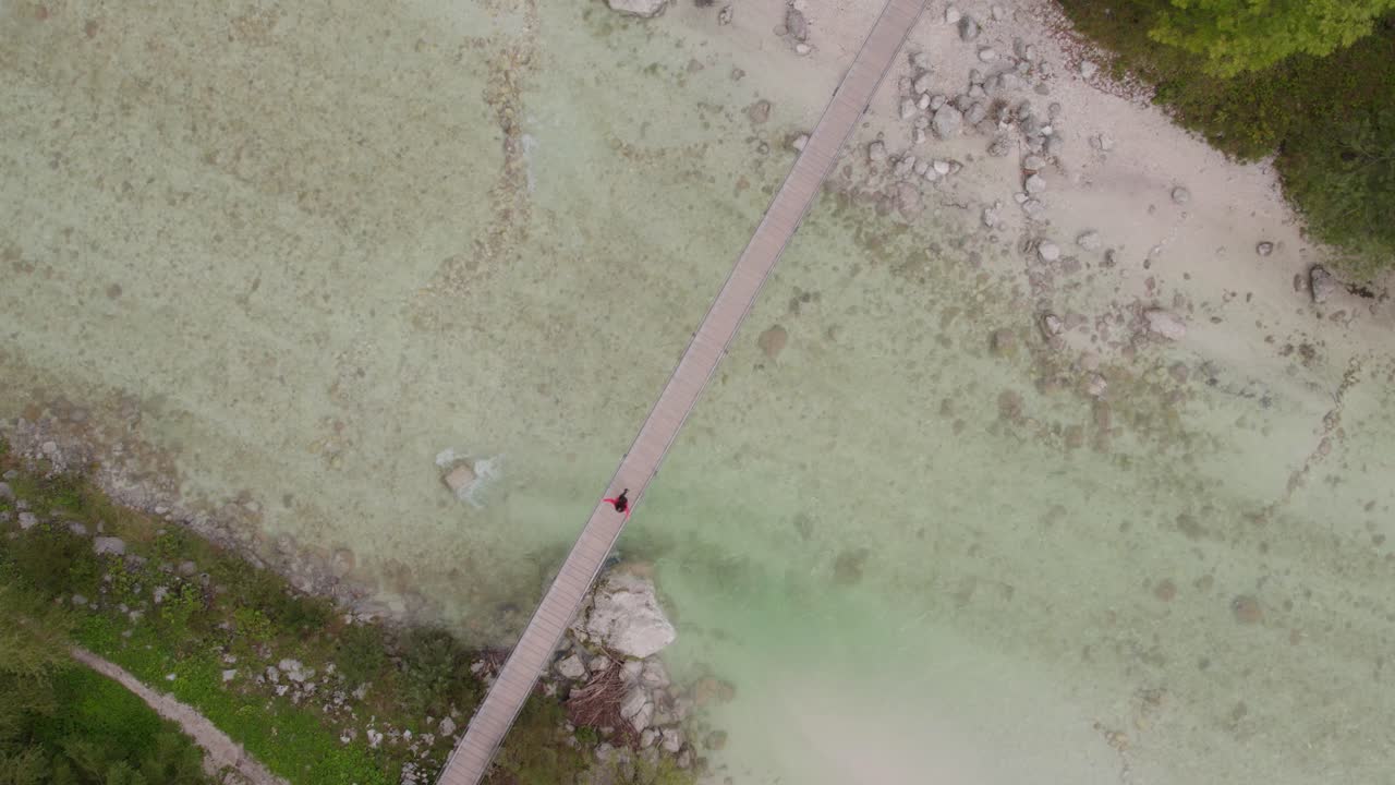 abajo de la parte superior del puente colgante con la mujer por encima de un río tranquilo en el valle de soca, aérea