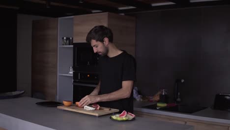 Portrait-of-a-man-cutting-grapefruit-on-chopping-board-and-funny-dances