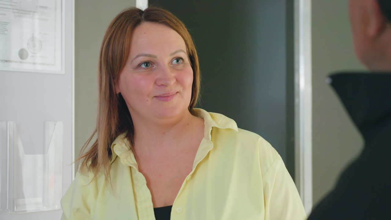 Il proprietario di una lavanderia con una maglietta gialla parla cordialmente con un cliente vicino al bancone all'interno di una lavanderia a gettoni, conversazione amichevole, assistenza clienti e ospitalità, interazione commerciale locale, sorriso accogliente