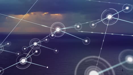 animation of network of connections over sea and cloudy sunset sky