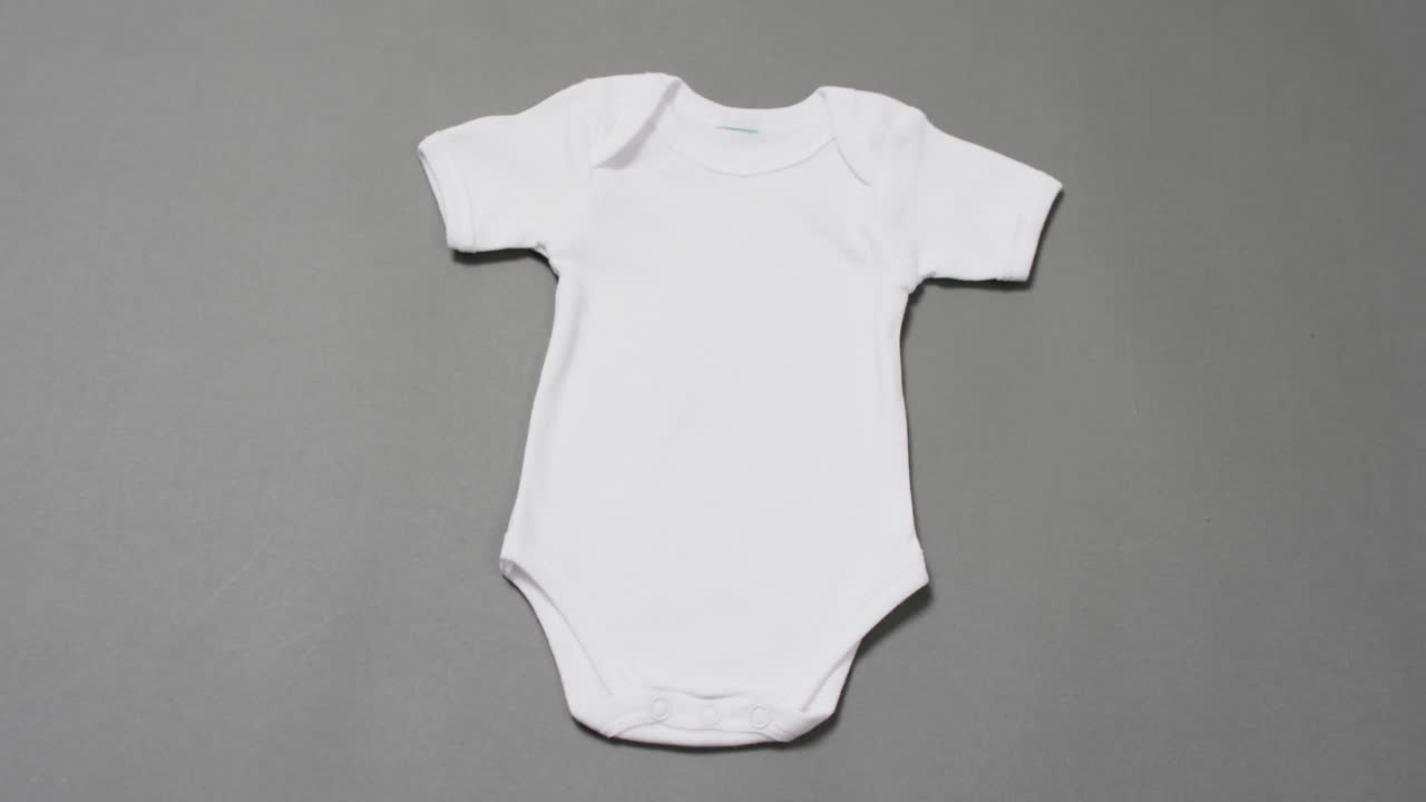 Video of white baby grow with copy space on grey background