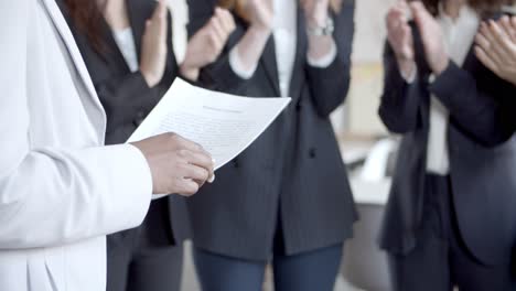 líder sosteniendo papeles y colegas aplaudiendo