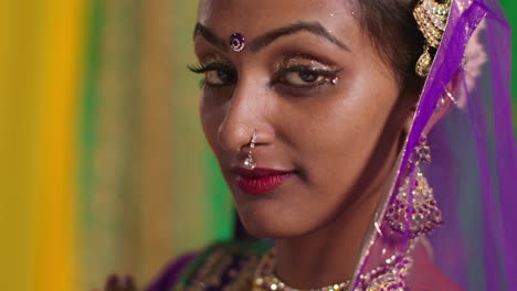 close up portrait of female kathak dancer performing dance wearing traditional indian dress and jewellery looking at camera