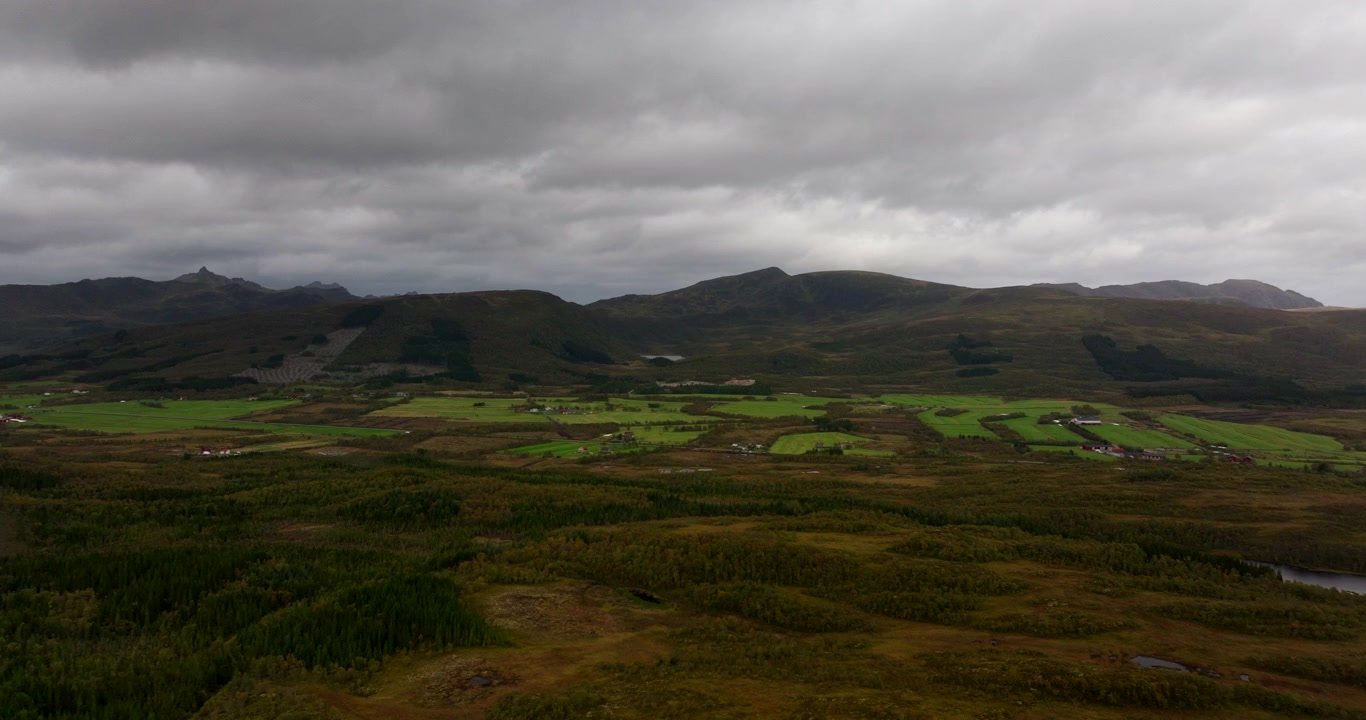 Overskyet himmel over fjellkjede og jorder nær Sortland by i Nordland fylke, Norge. Luftfoto med drone