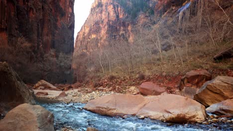 Looking-up-towards-sun-in-rocky-canyon-gorge-with-gurgling-stream,-POV