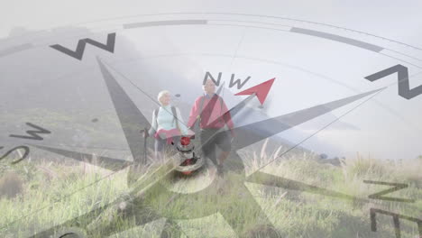pareja de ancianos caucásicos caminando en el campo montañoso tomados de la mano, girando la brújula
