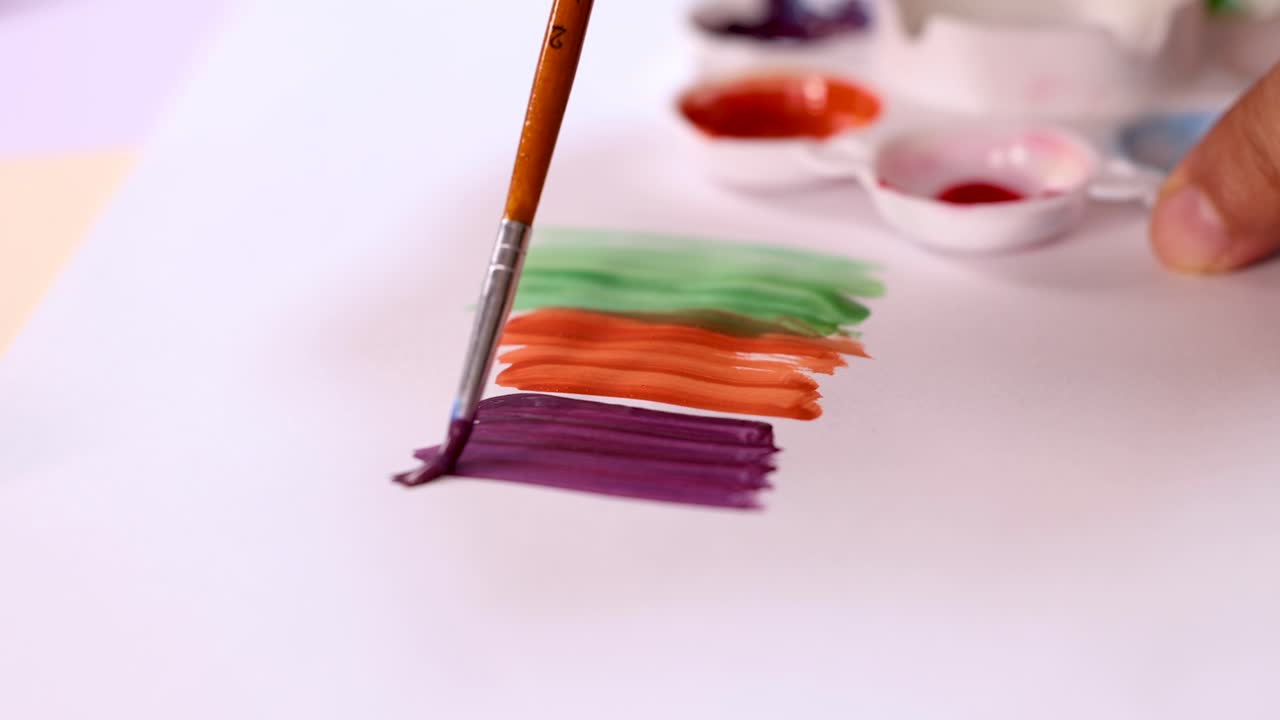 Artist hand paints layered watercolor stripes using brush, vibrant palette, and soft natural lighting