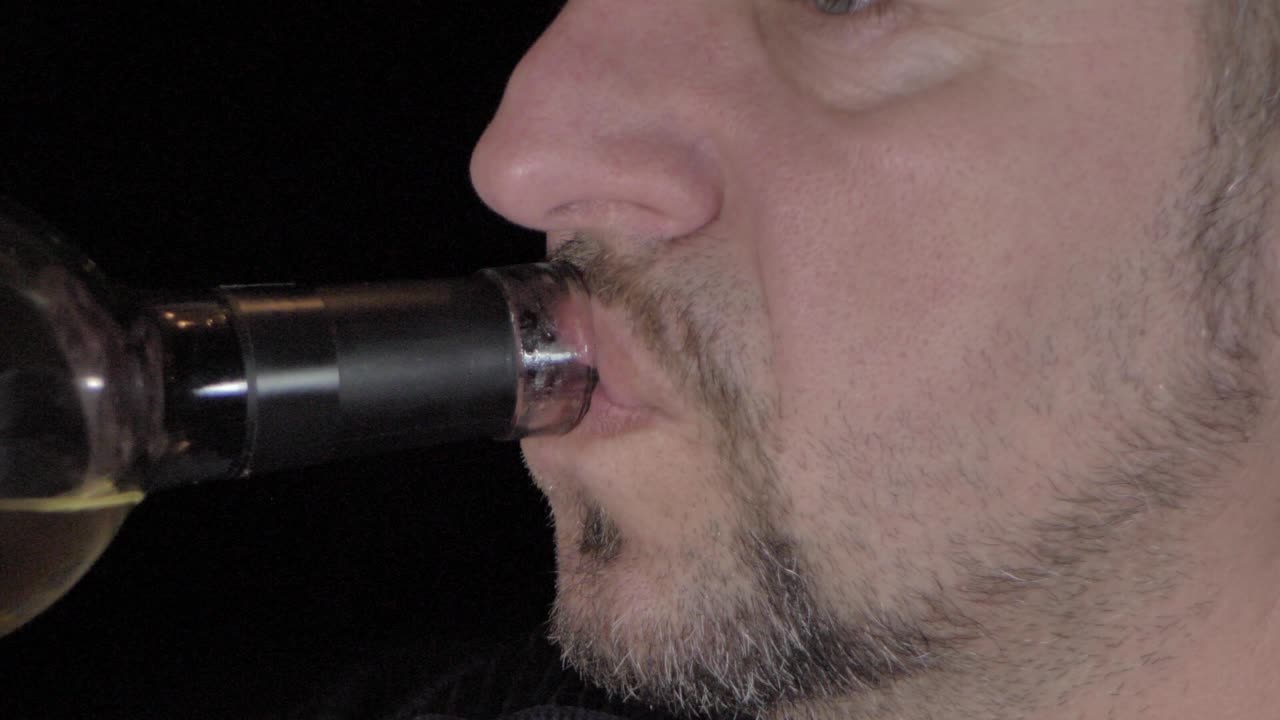 un hombre con barba bebe vino de una botella