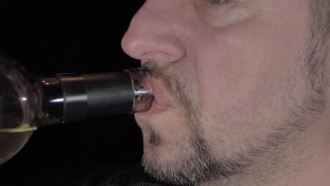 a man with a beard drinks wine from a bottle