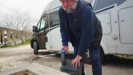 man pours toilet cassette from rv into black water sink