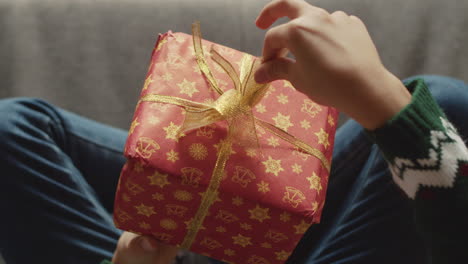 Vista-Superior-De-Un-Niño-Irreconocible-Sentado-En-El-Sofá-Y-Jugando-Con-Una-Caja-De-Regalo-De-Navidad