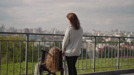 young mother shows city view to daughter with disability