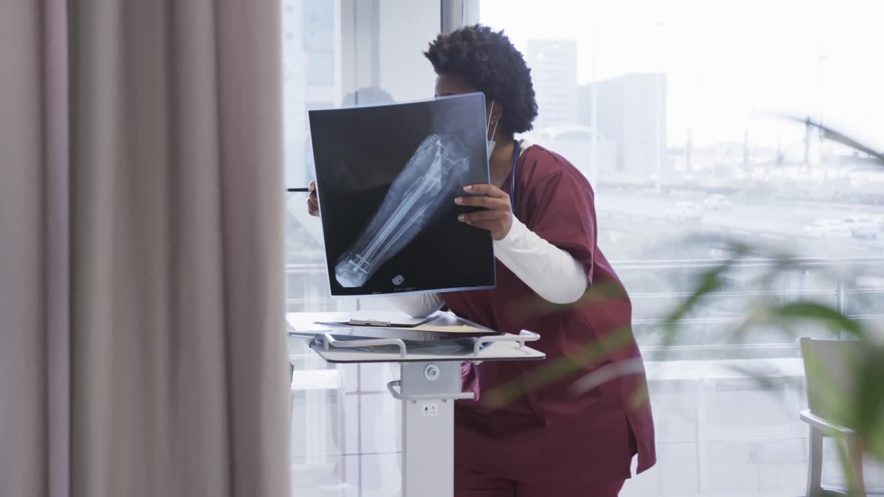 African american female doctor discussing x ray image in hospital room, slow motion