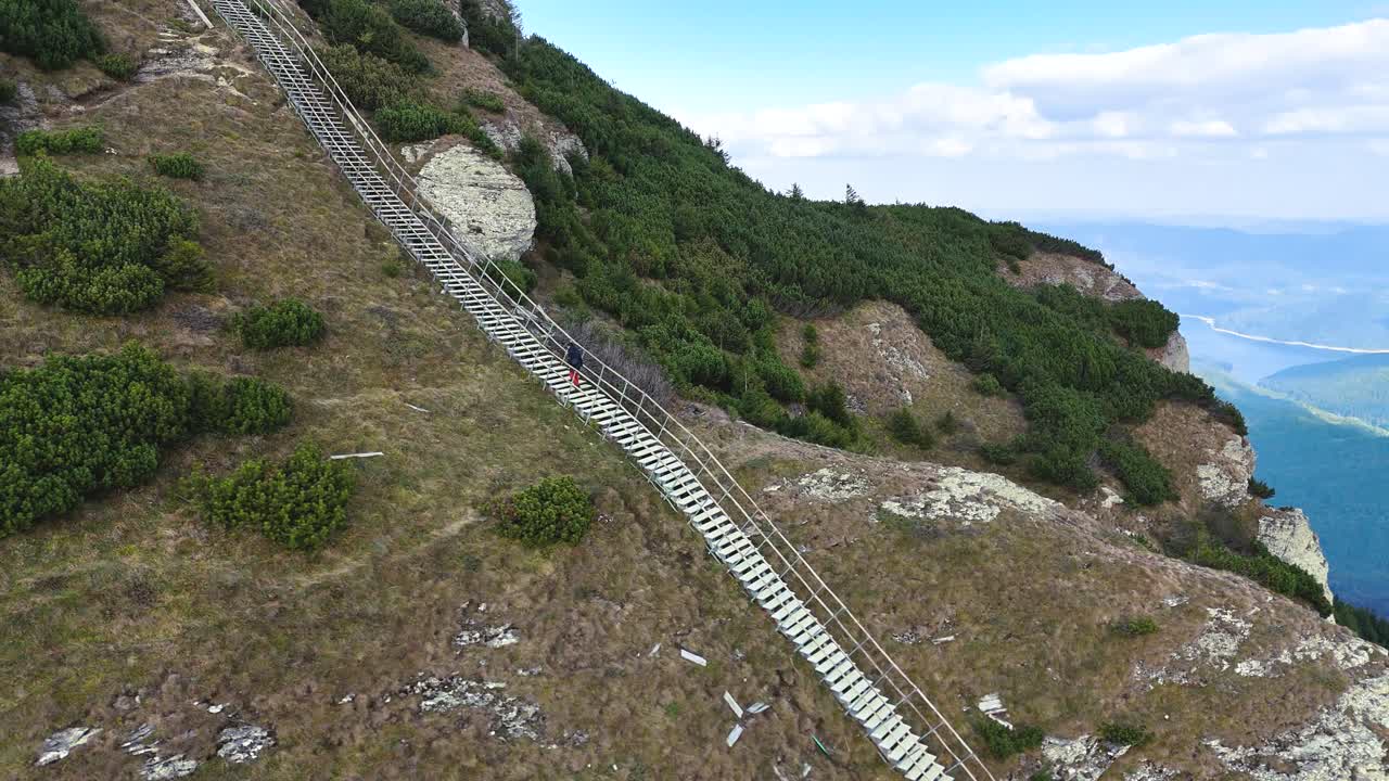 Drone captures male climber ascending ladder on Toaca Peak, Romania
