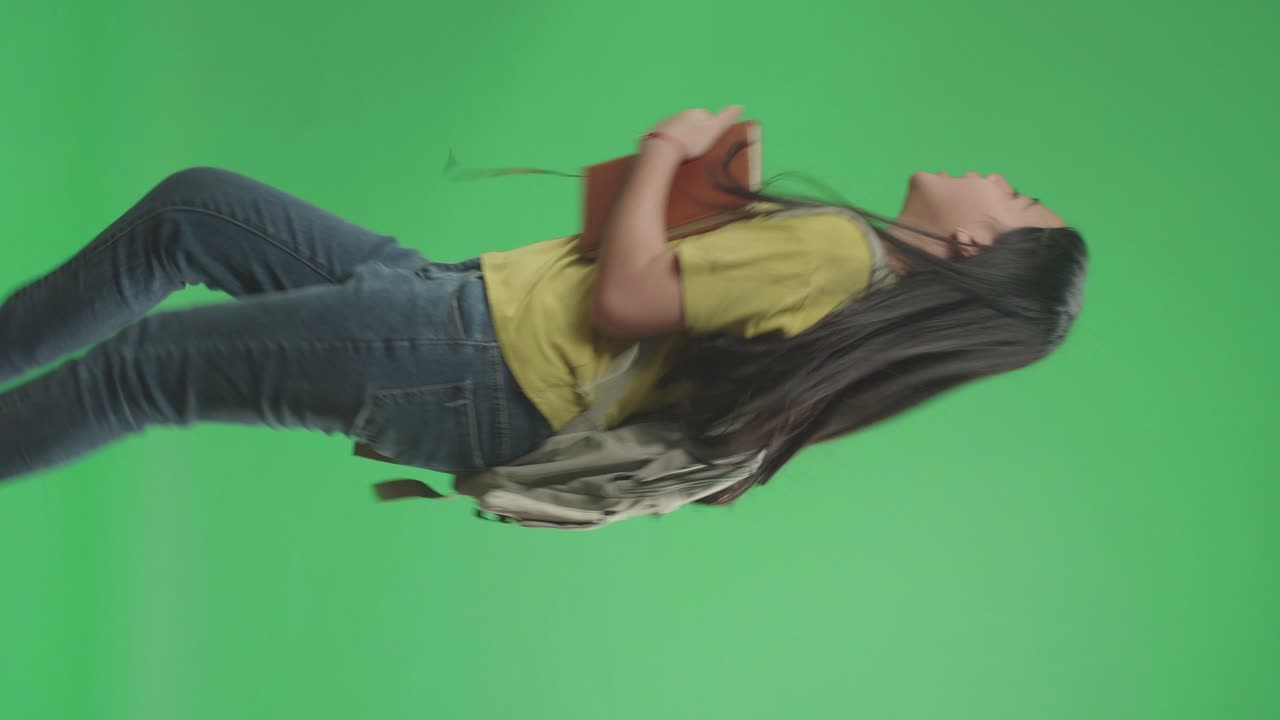 Side View Of Asian Girl Student Holding Book While Running To School On Green Screen Chroma Key