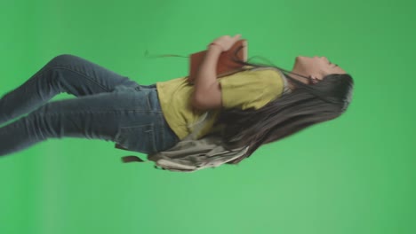 vista lateral de una estudiante asiática sosteniendo un libro mientras corre a la escuela en pantalla verde clave de croma