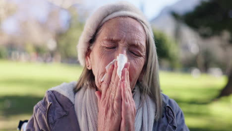 senior woman blowing her nose in the park