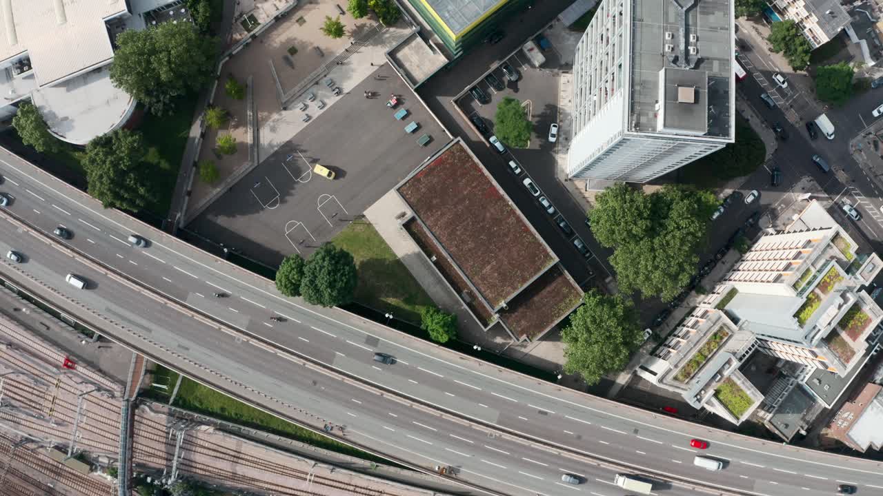Ripresa aerea con drone dall'alto di un'autostrada trafficata e di una linea ferroviaria che circondano un'area residenziale.