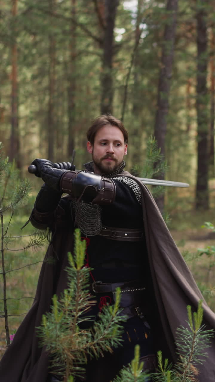 un noble en armadura con capa enseña a los campesinos a luchar con la espada preparándose para la guerra en cámara lenta. escena de la edad media. actores en trajes vintage juegan papeles