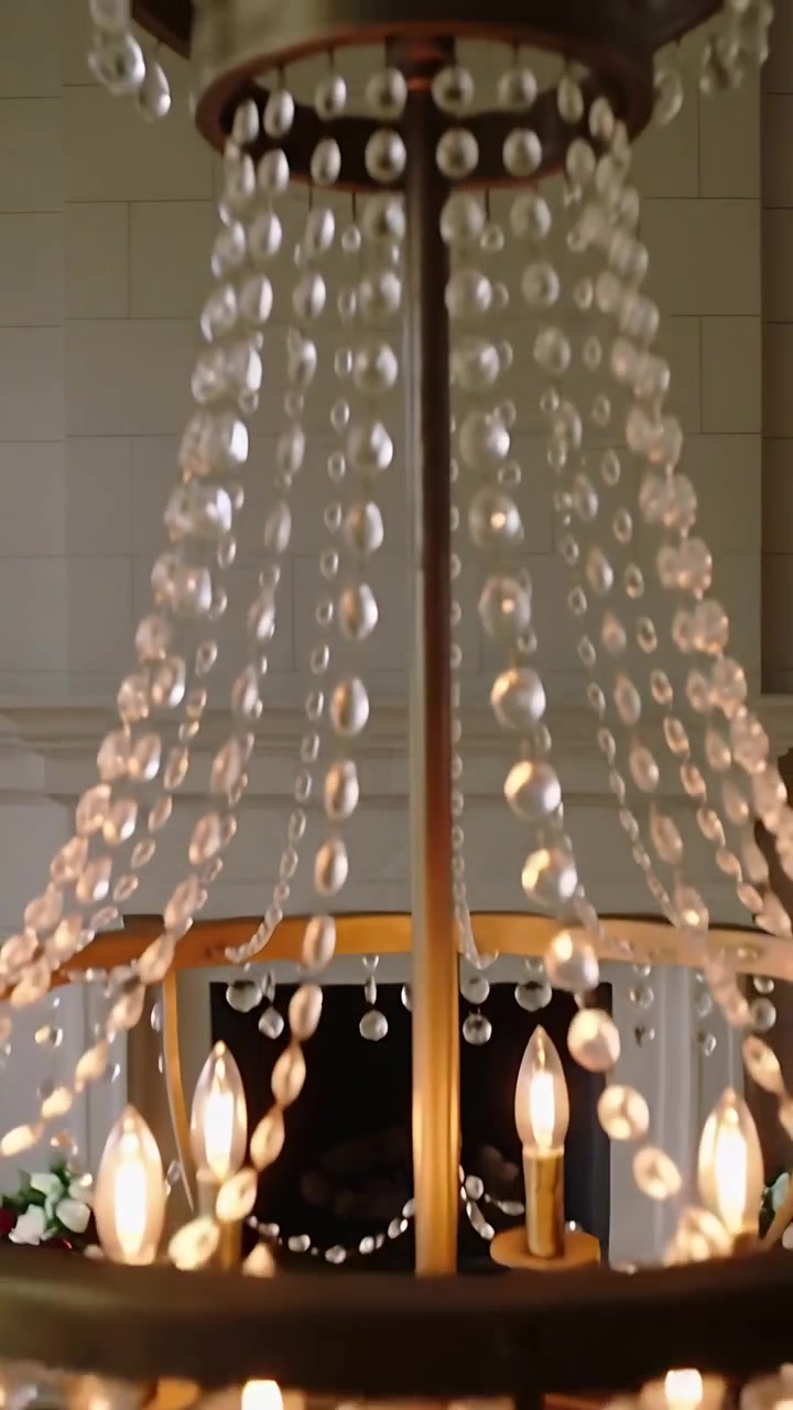 Video verticale: Telecamera che si inclina rivelando un lampadario di cristallo sopra il caminetto, catturando la calda luce delle candele.