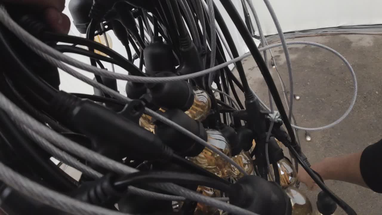 Close Up of Hands Coiling Decorative String Lights with Edison Bulbs