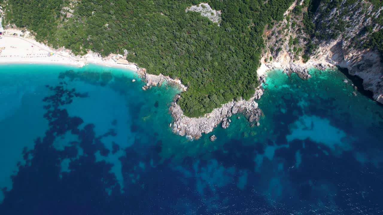 알바니아 의 이오니아 해 의 원시 해안선 은 깊은 파란색 바다 와  ⁇  모래 를 가진 아름다운 해변 으로  ⁇ 여 있는 절벽 에 있는 동굴 들 을 가지고 있다