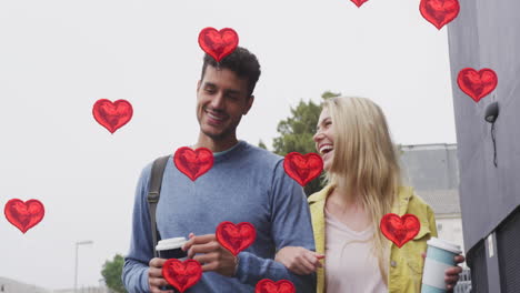 animación de iconos de corazón flotando sobre una feliz pareja caucásica caminando y bebiendo café para llevar
