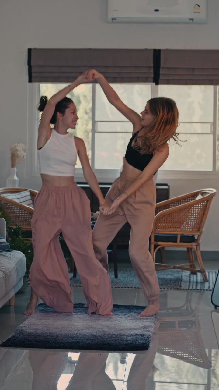 Two Young Women Dancing and Having Fun in a Living Room