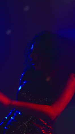 Vertical-Video-Of-Young-Woman-In-Nightclub-Bar-Or-Disco-Dancing-With-Sparkling-Lights-In-Background-2