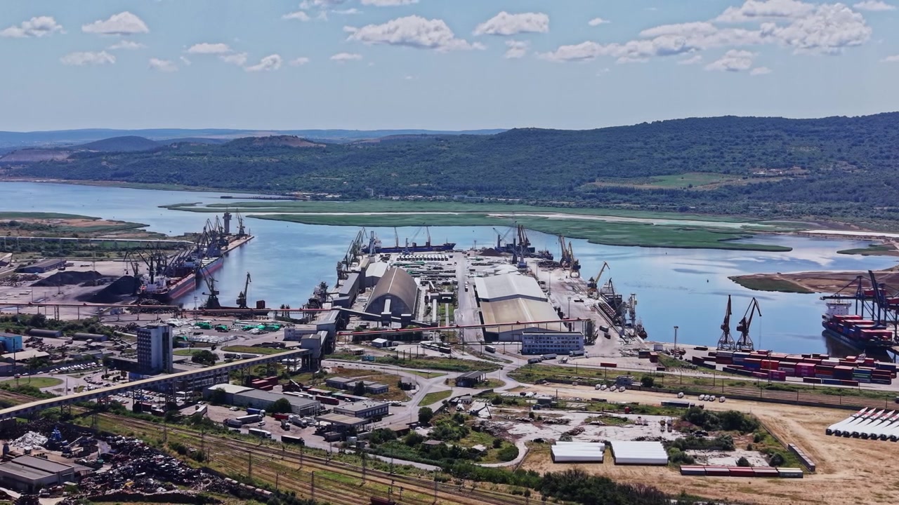 Area portuale con navi e container da carico vicino a un fiume e colline