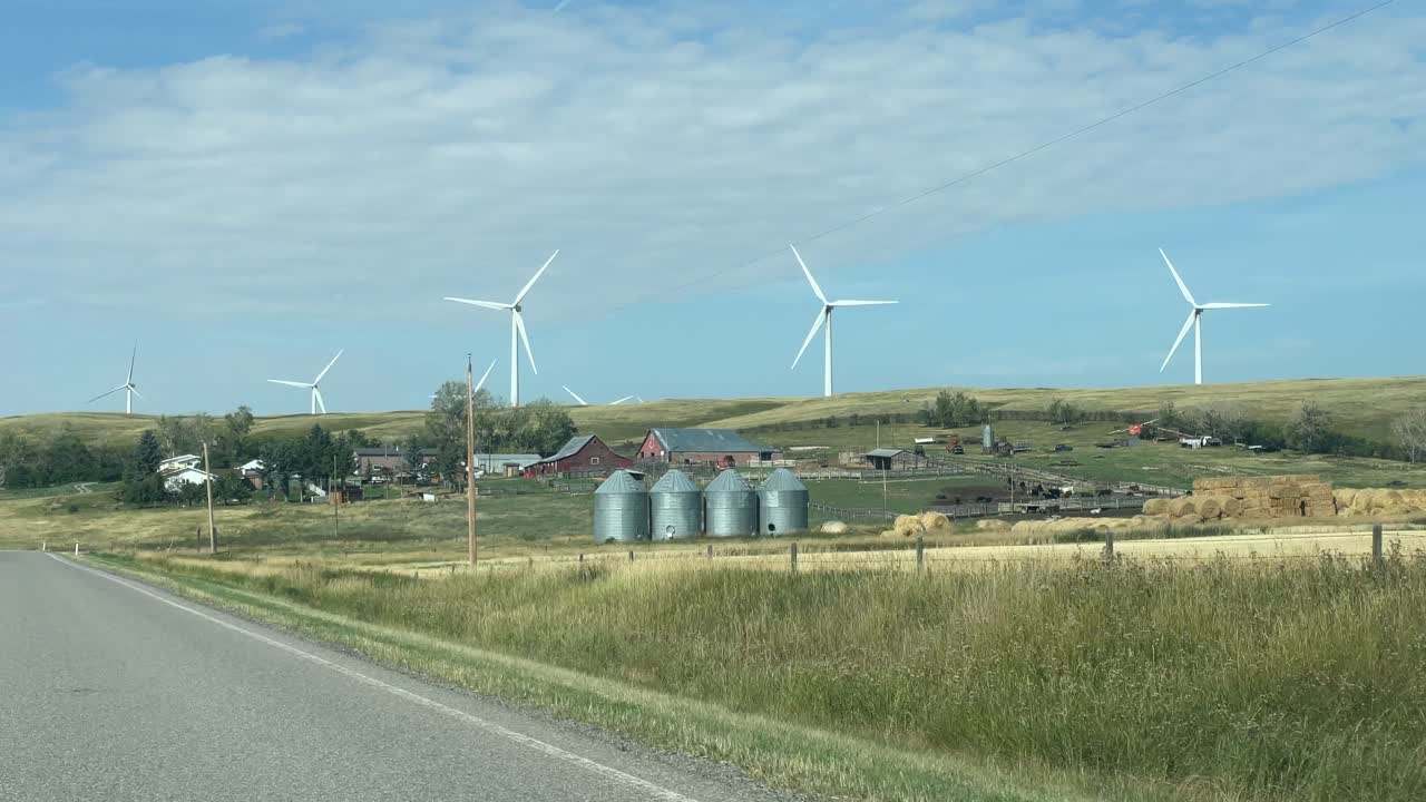Farm on the side of the road with Windmills spinning in the background, Alberta, Canada