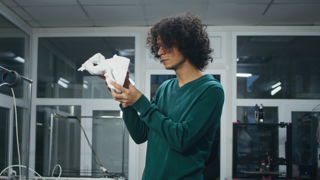 Man Examining a 3D Printed Object in a Technology Workshop