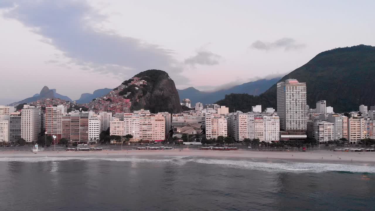 acercamiento aéreo hacia adelante del barrio de copacabana en río de janeiro temprano en la mañana con la playa y el bulevar en primer plano y el horizonte de la ciudad en el fondo