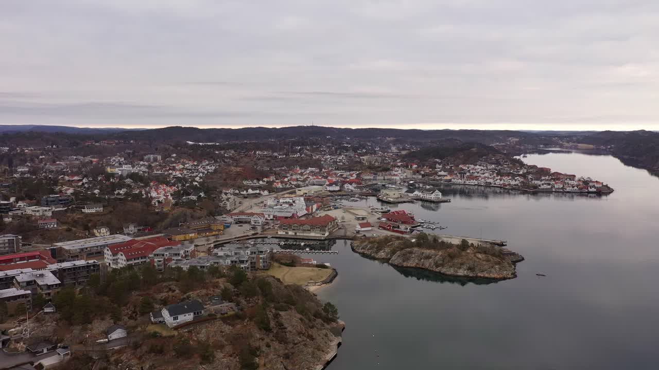 Flygfoto som närmar sig Grimstad stad över havet med mjuka reflektioner under morgonen – Vita trähus och marina i södra Norges skärgård