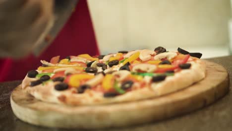 moving foward close up shot of cutting pizza by chef with pizza cutter