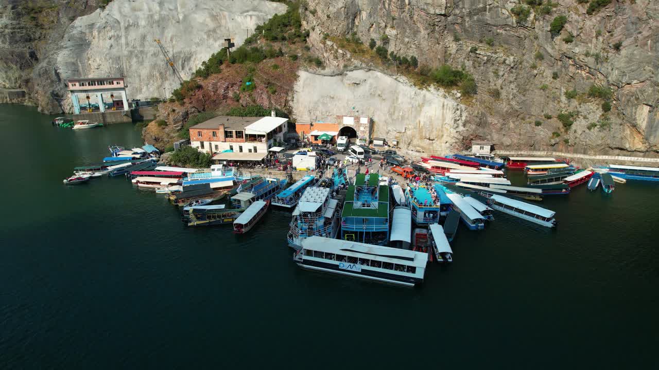 Tourists emerge from the hydroelectric tunnel and embark on boats and ferries at Dock of Koman Lake, ready to explore the alpine beauty of Shala River and Valbona Valley in Albania