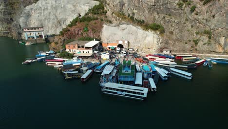 tourists emerge from the hydroelectric tunnel and embark on boats and ferries at dock of koman lake, ready to explore the alpine beauty of shala river and valbona valley in albania