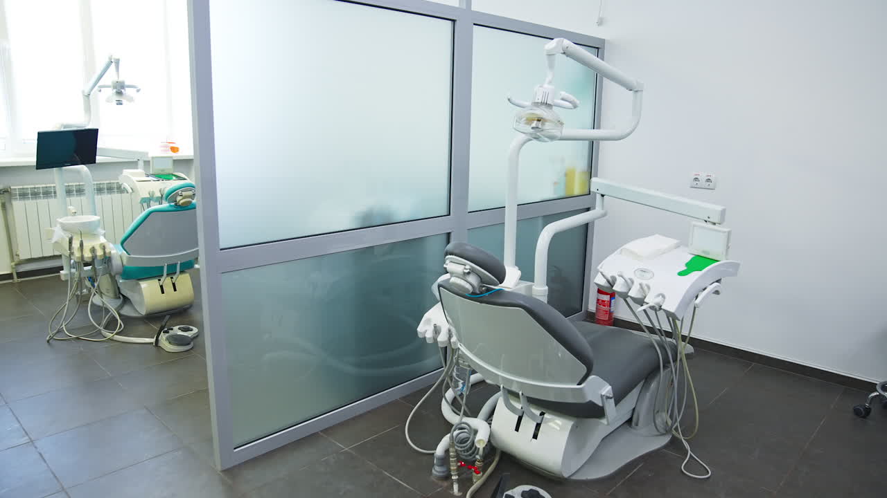 Minimalistic working place of a modern dentist. Light big room divided into several working areas. Comfortable armchair for patients of dentistry professionals.