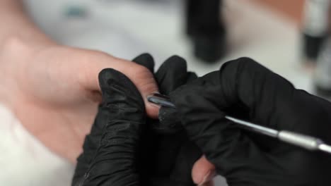 beauty therapist pushing back the cuticles of a clients hand for a manicure