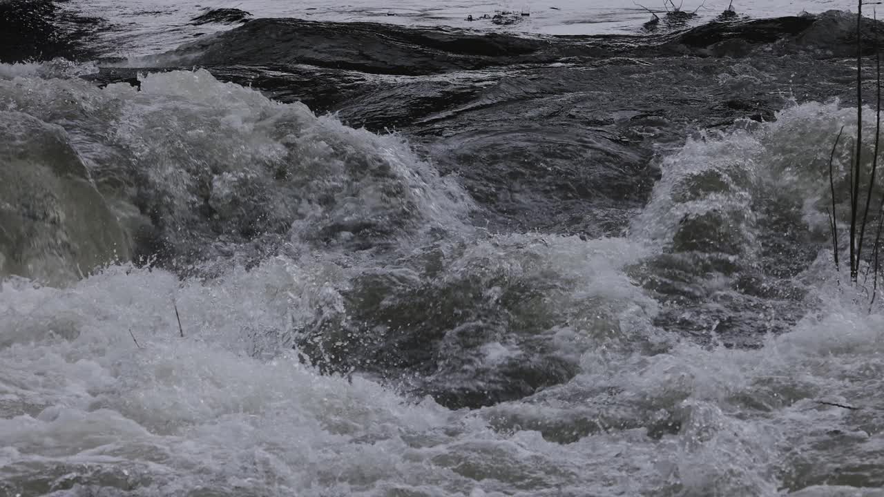 Slow motion shot of white water rapids on a raging river after heavy rainfall