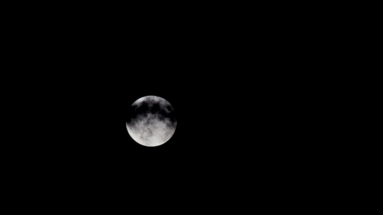 Full moon behind the dramatic clouds on a night sky