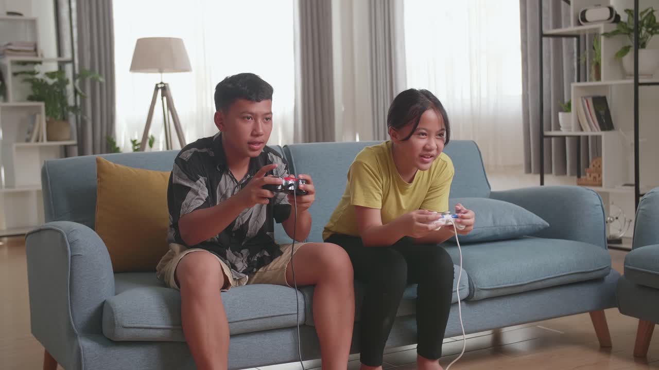 Asian Children With Joystick Game Playing Video Games At Home