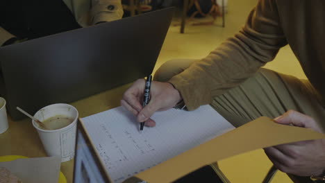 manos de un hombre de negocios haciendo notas en un cuaderno en una cafetería. hombre freelance trabajando